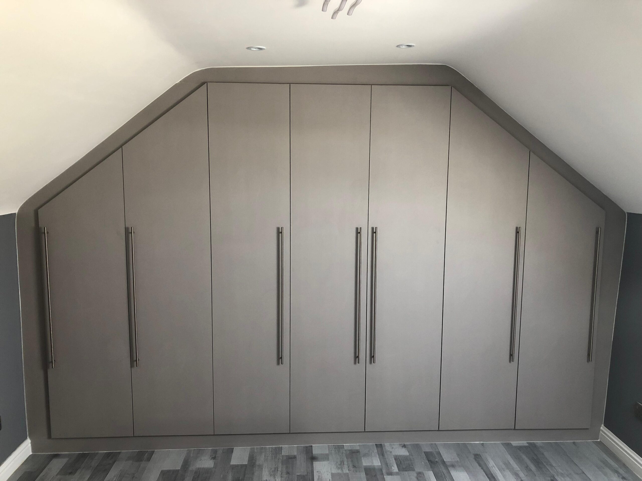 Modern loft wardrobes built into a sloped attic ceiling for smart storage in a UK home.