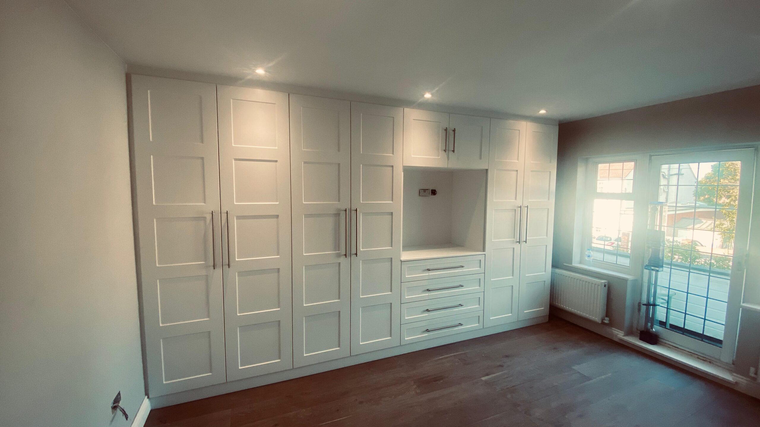 Elegant bespoke wardrobes in a modern bedroom showing high quality built-in storage and custom shelving.