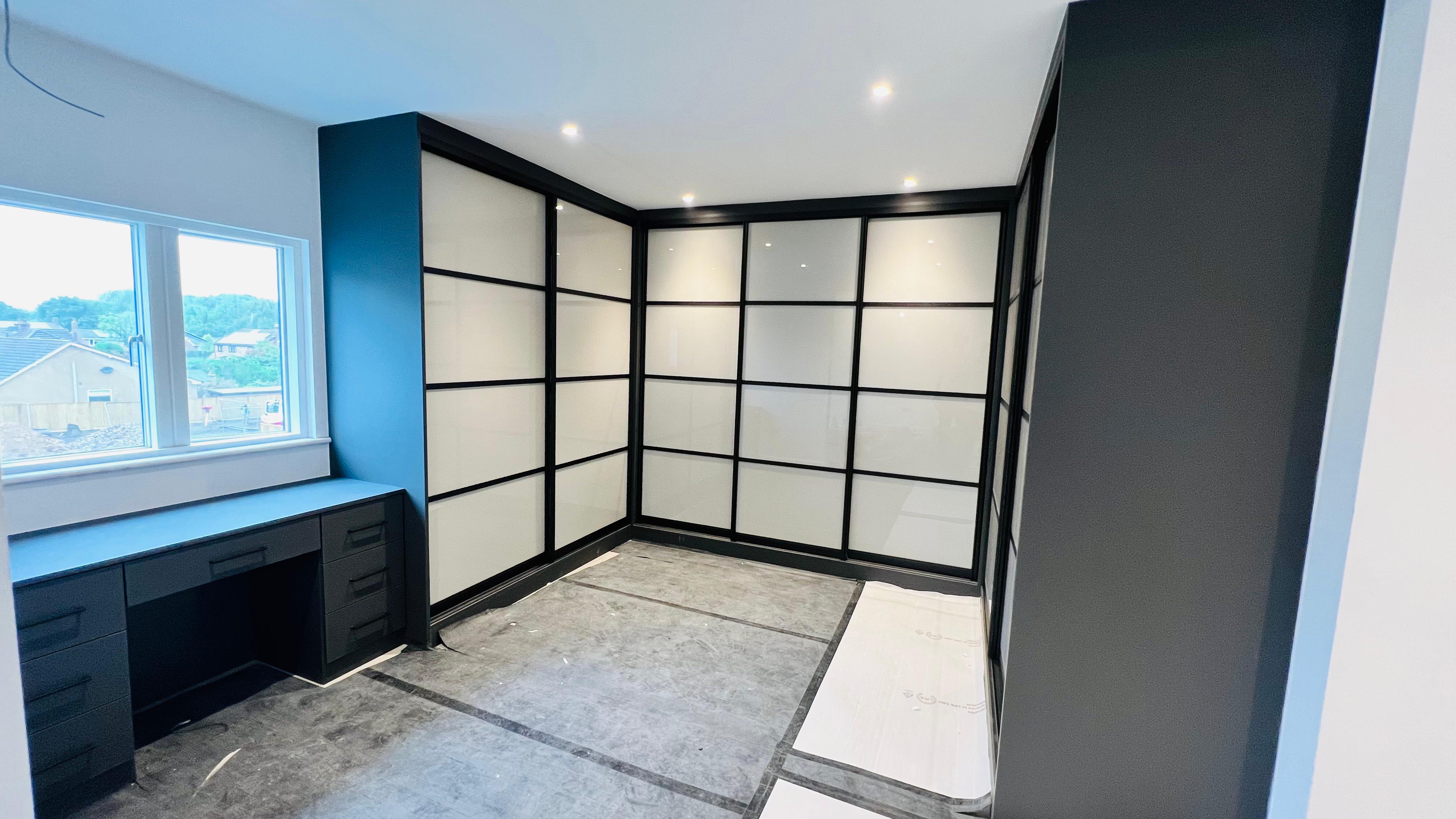 Modern custom fitted wardrobes in a tidy bedroom showing sleek doors and high quality storage solutions in a UK home.