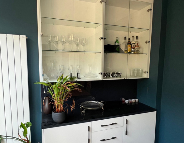 Stylish bespoke home bar with fitted bar cabinet and modern bar stools in a luxury UK interior